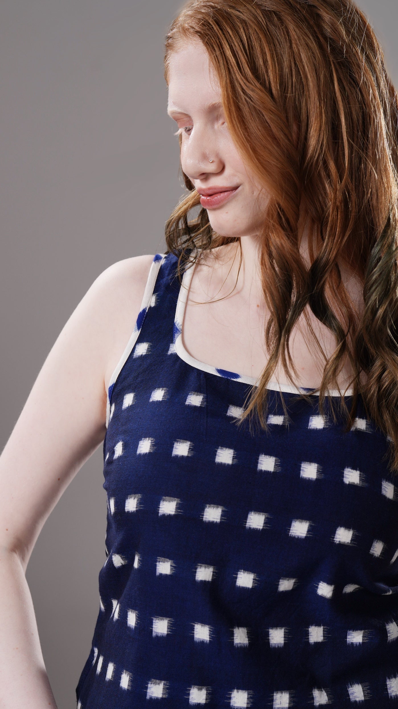 Woman wearing a navy blue top with white polka dots against a gray background
