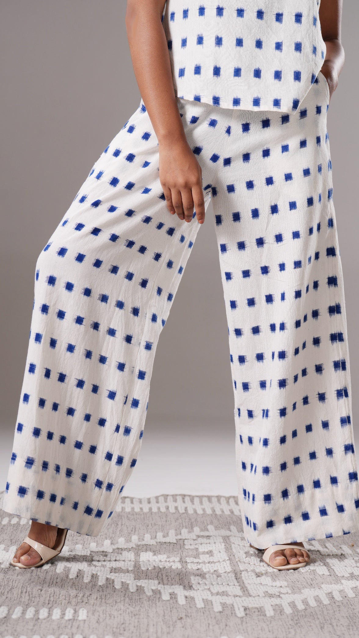 Person wearing white pants with blue square pattern on a neutral background