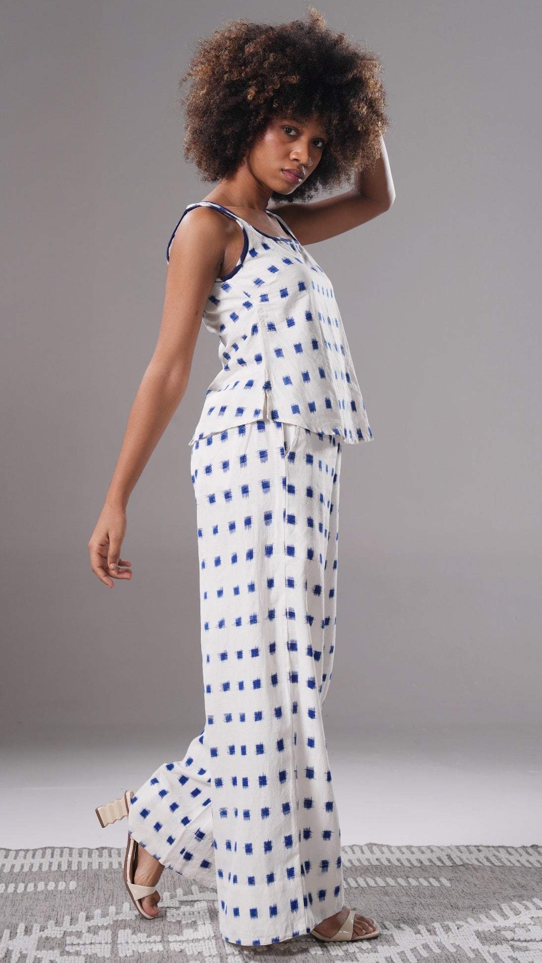Woman wearing a white dress with blue patterns on a gray background