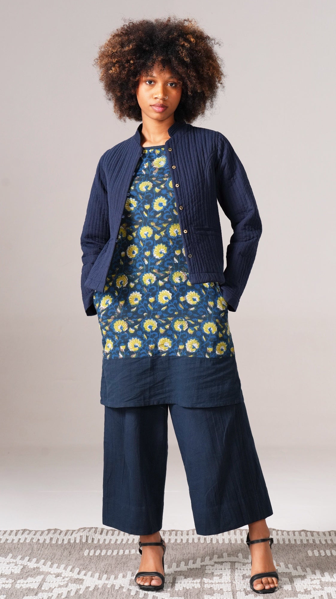 Woman wearing a navy outfit with a floral top and wide-leg pants on a plain background