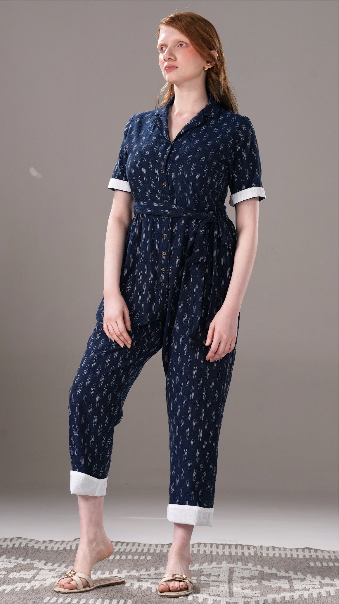 Woman wearing a navy blue patterned jumpsuit on a gray background