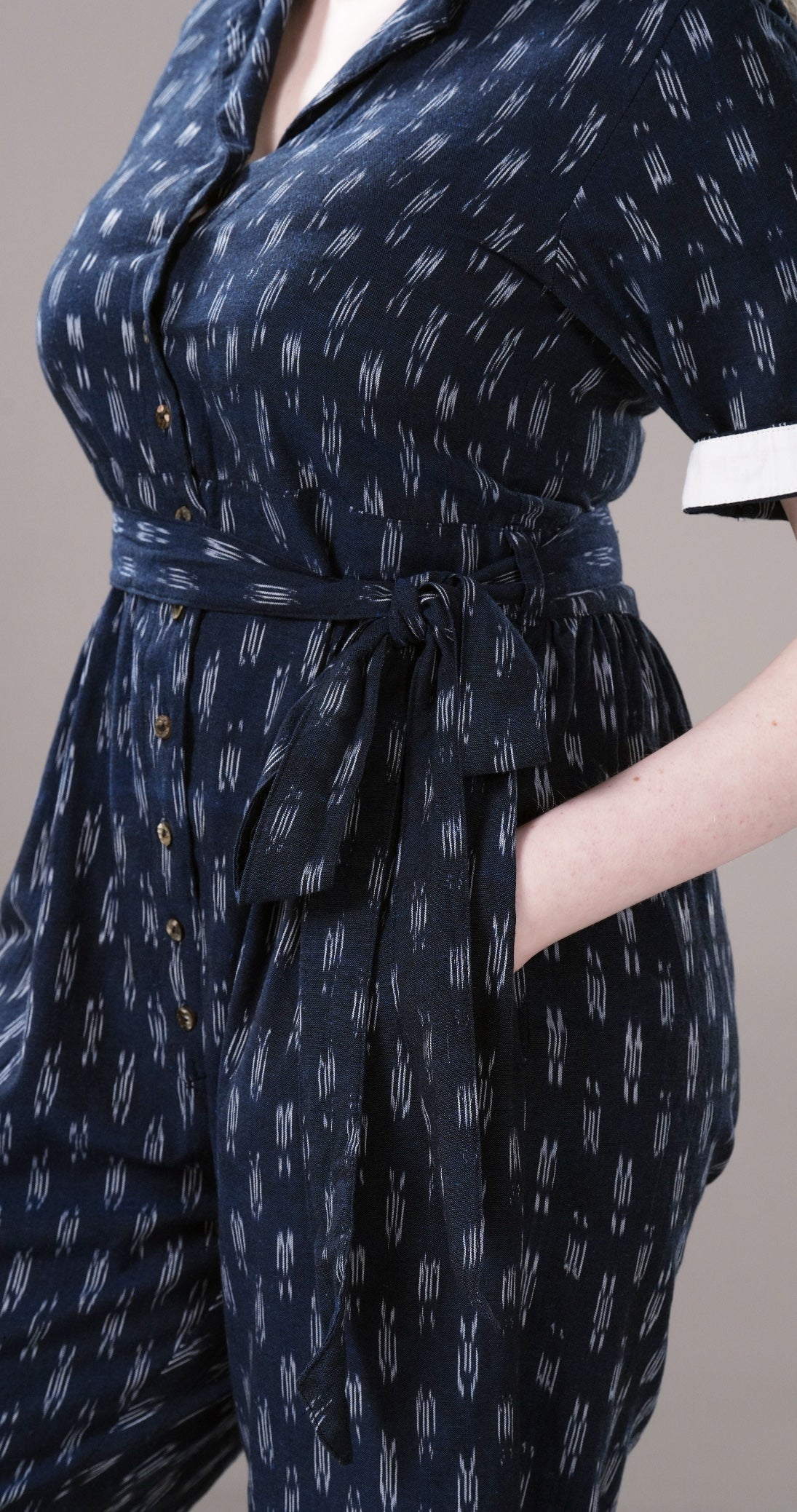 Navy blue patterned dress with a belt on a neutral background