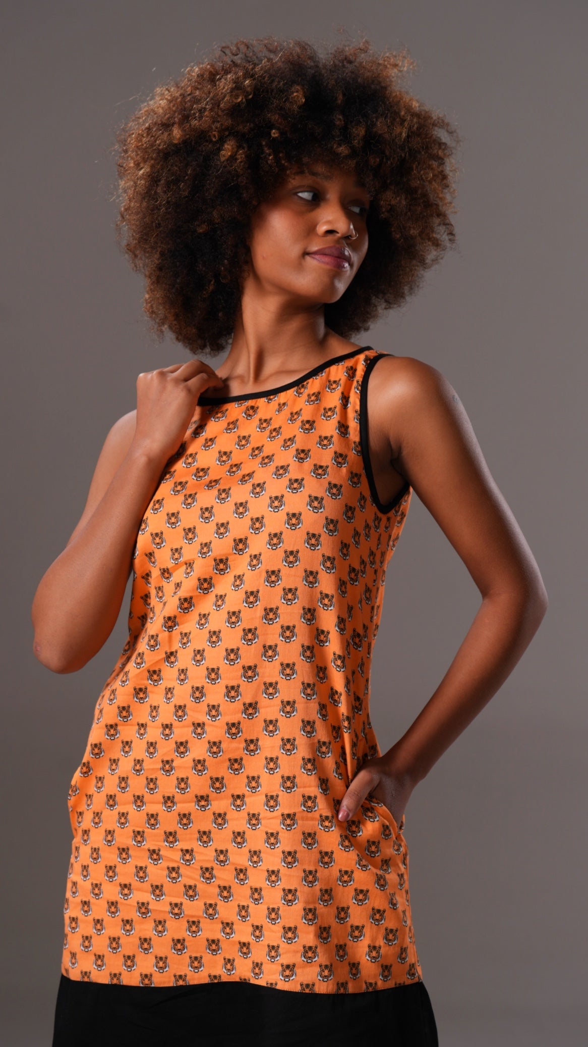 Woman wearing an orange dress with black cat pattern on a gray background