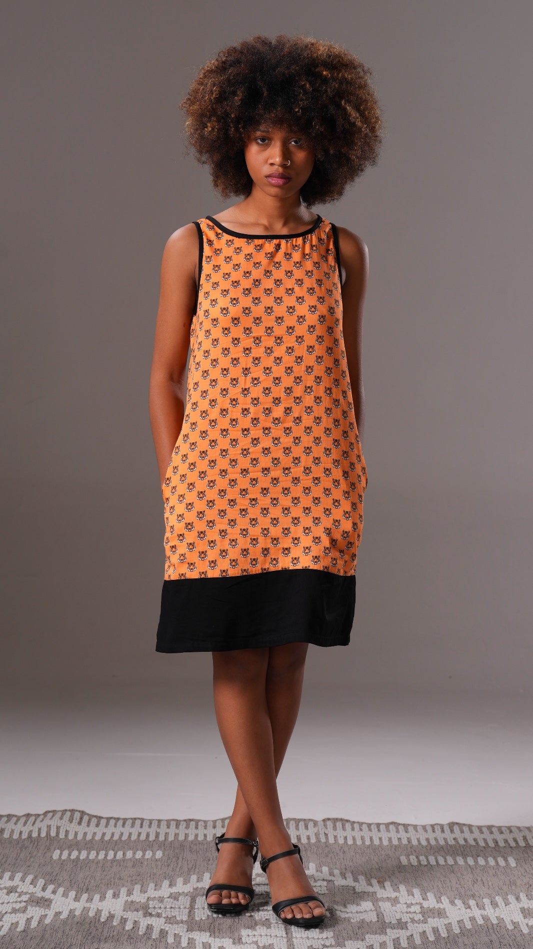Woman wearing an orange and black patterned dress on a gray background