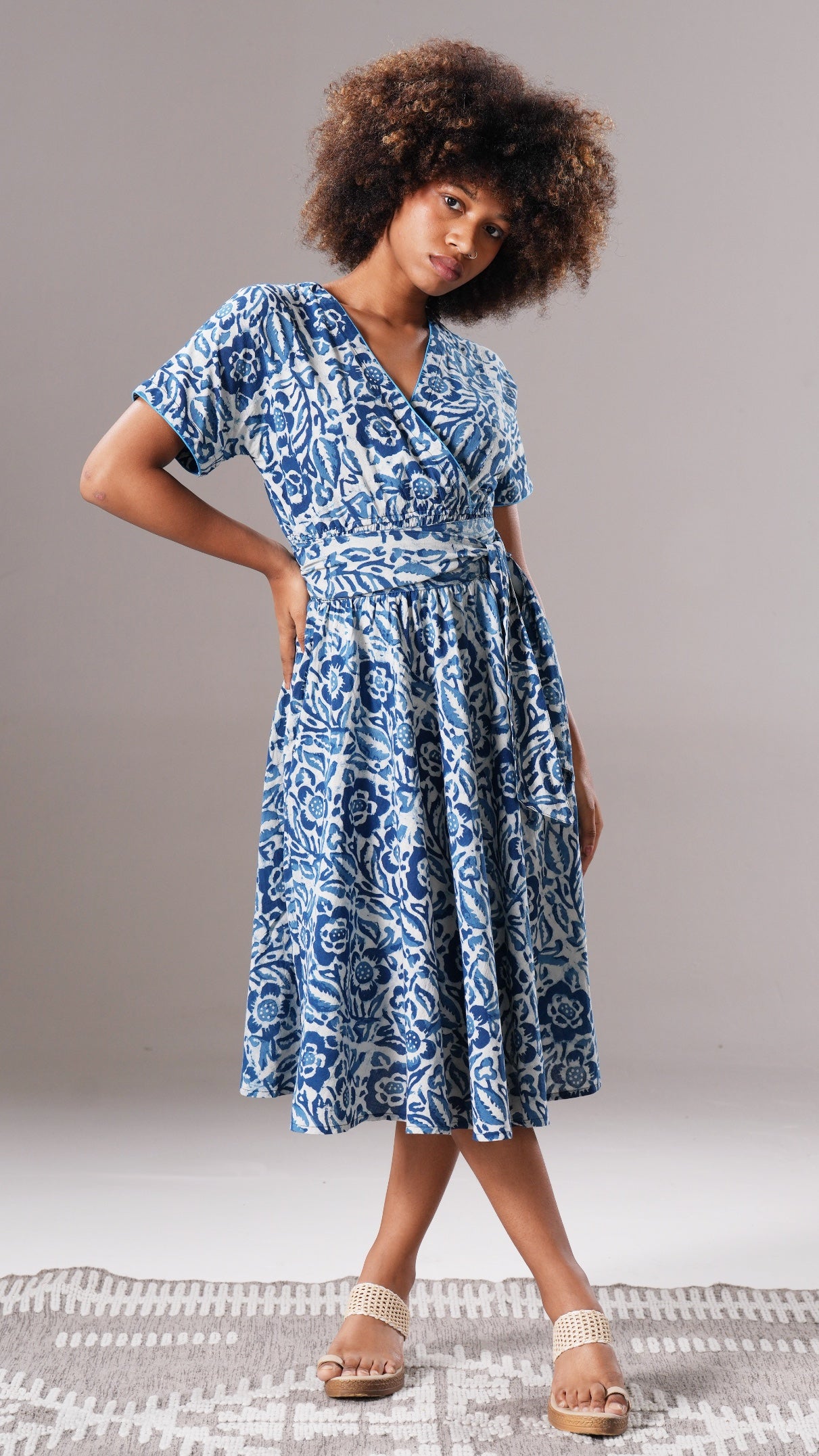 Woman wearing a blue and white patterned dress on a gray background