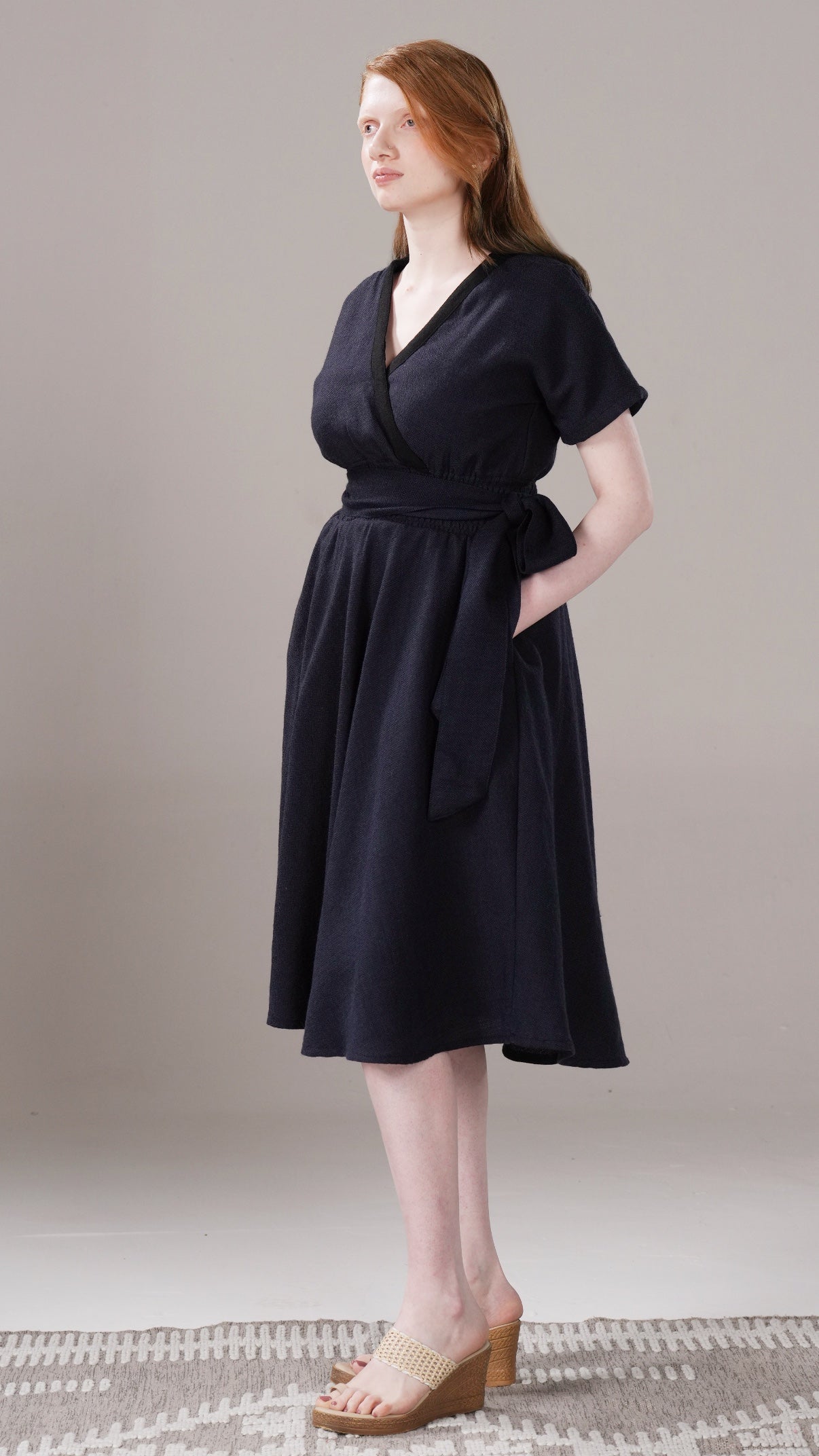 Woman wearing a black dress standing on a neutral background